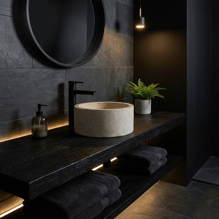 Round countertop washbasin in an elegant marble look on a dark wooden console, staged in a minimalist dark mood bathroom.