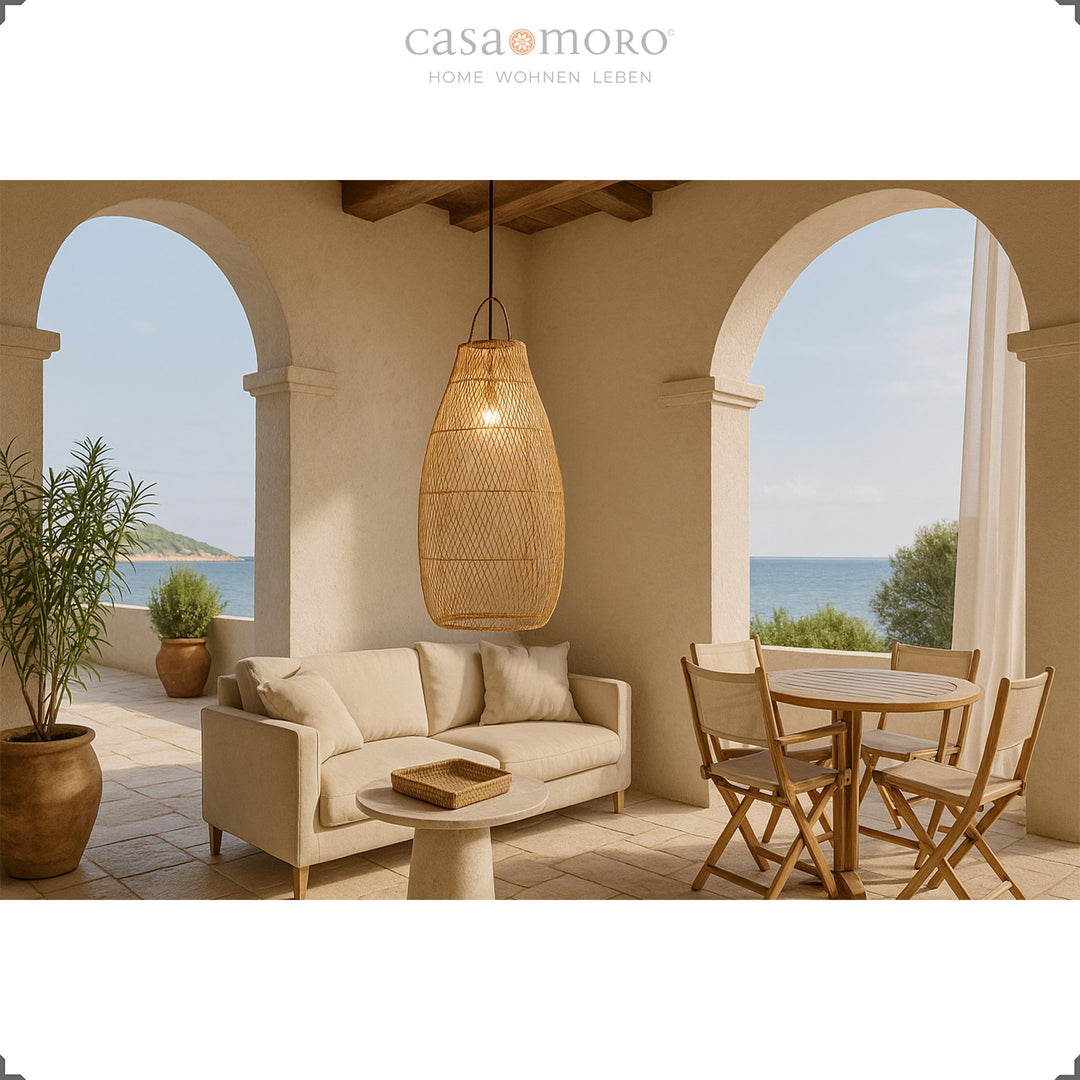 Grande lampe en rotin sur la terrasse méditerranéenne au-dessus de la table à manger et du canapé avec vue sur la mer