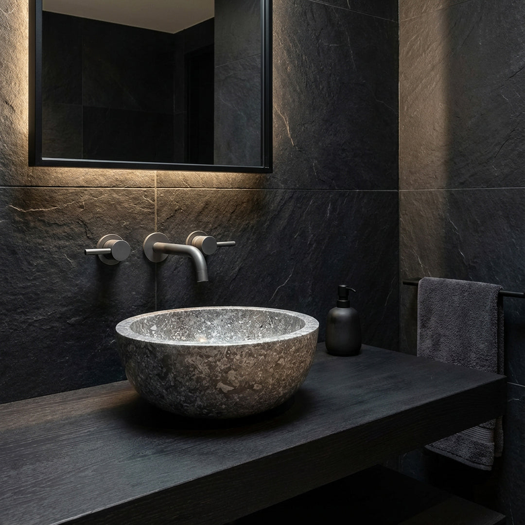 Rond Lavabo en pierre naturelle foncée comme fixation sur une console noire dans une ambiance de salle de bain moderne et minimaliste