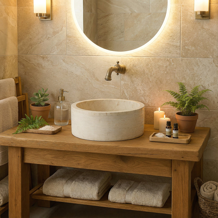 Round countertop washbasin made of light marble on a wooden washbasin, harmoniously staged in the warm spa bathroom with candles.