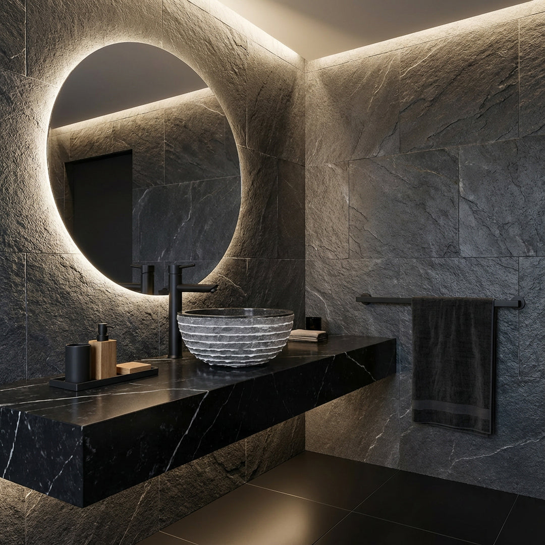 Lavabo rond en pierre naturelle sur meuble-lavabo sombre dans une salle de bains spa moderne avec miroir, robinet noir et lumière indirecte