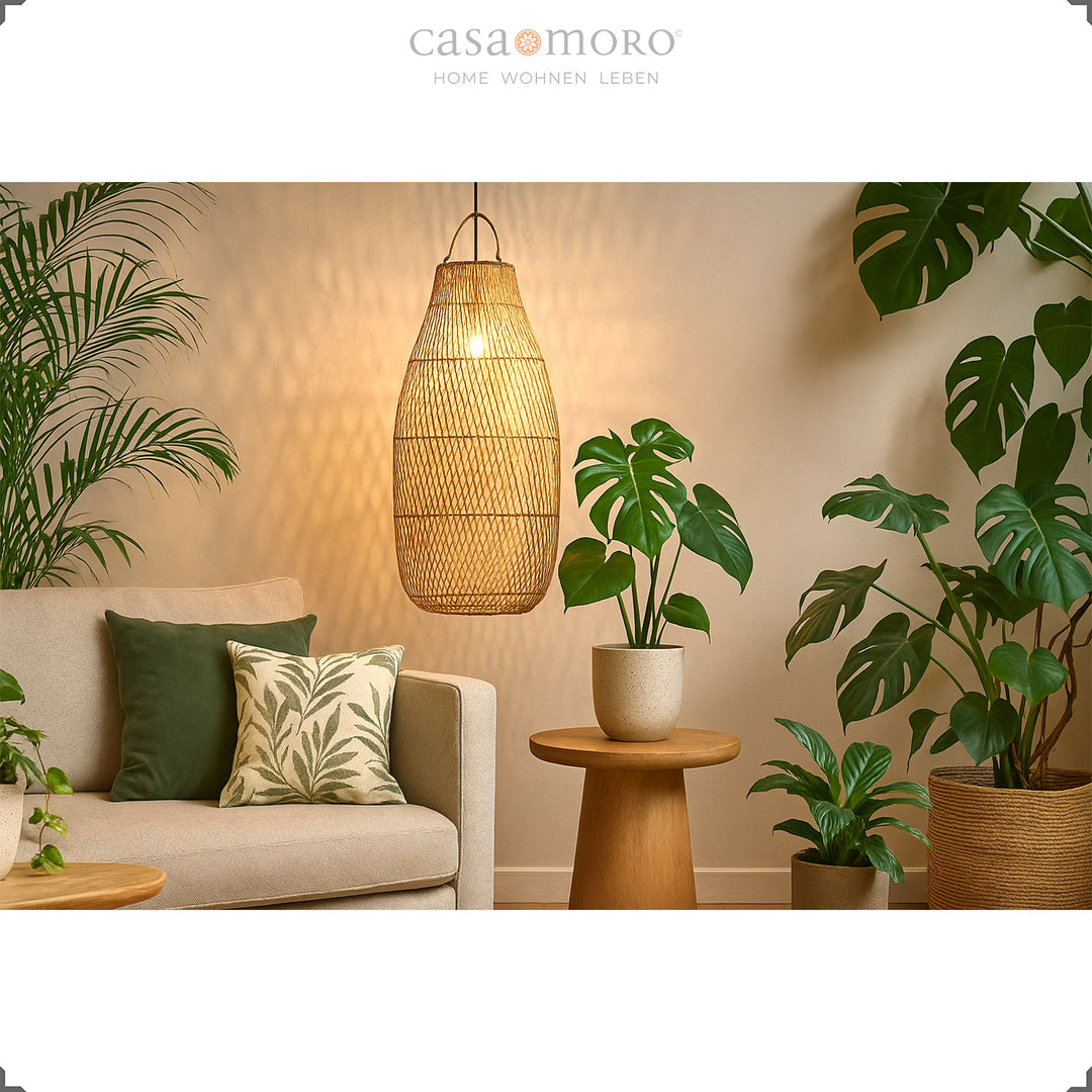 Grand plafonnier en rotin au-dessus du canapé dans le salon avec beaucoup de plantes vertes et une lumière chaude