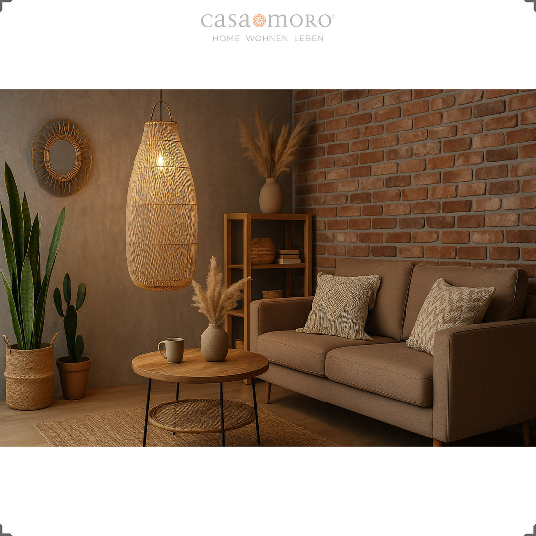 Grande lampe suspendue en rotin dans le salon avec un mur de briques et un jeu de lumière chaleureux