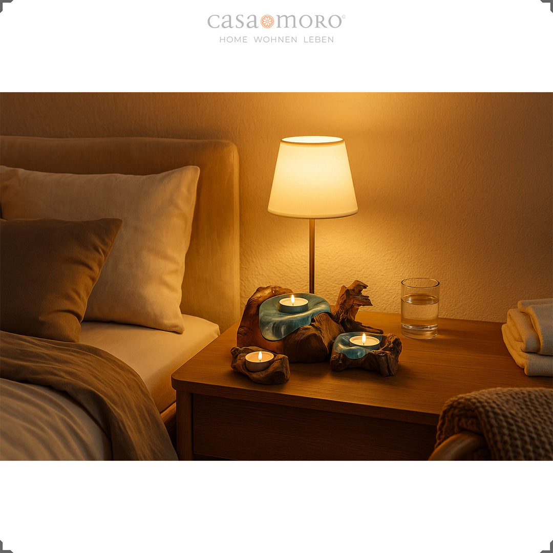 Three tea light holders made of glass and burl wood on a bedside table, whose soft candlelight creates a calming bedroom atmosphere.