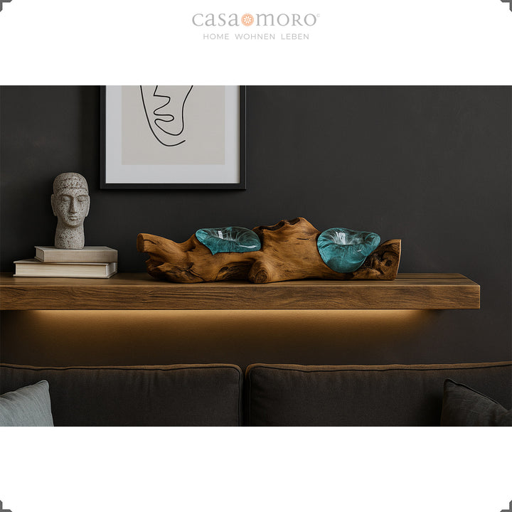 Photophore allongé en verre et bois de loupe sur une étagère murale, sa lumière chaude complète l'ambiance élégamment sombre du salon.