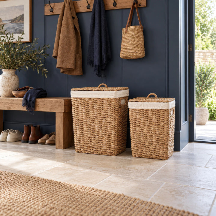 Zwei Wäschekörbe aus Seegras mit 50 und 90 Litern Volumen und geschlossenen Deckeln neben einer Holzbank im Flur.
