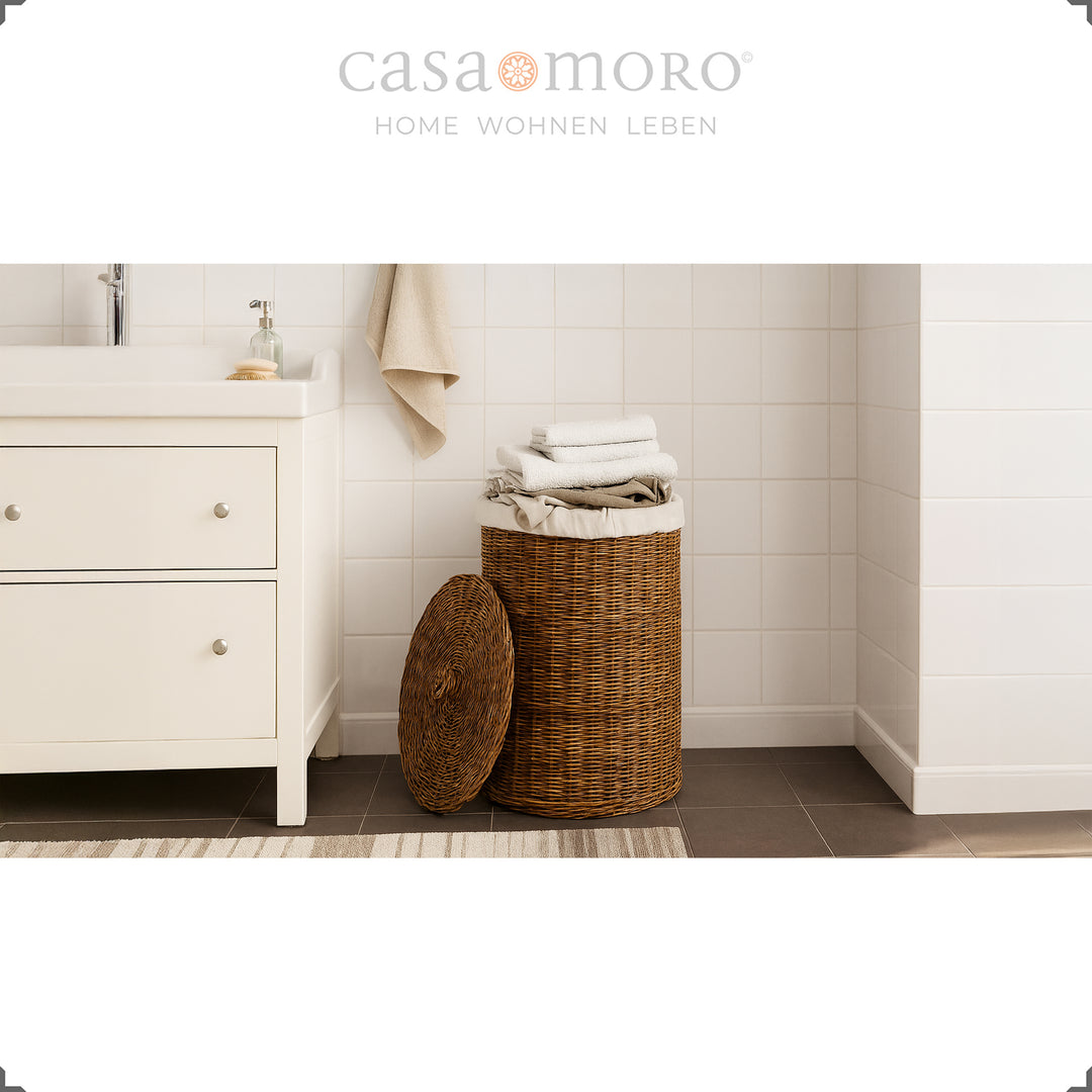 Panier à linge en rotin marron avec couvercle et insert en coton dans la salle de bain, rempli de serviettes de manière décorative