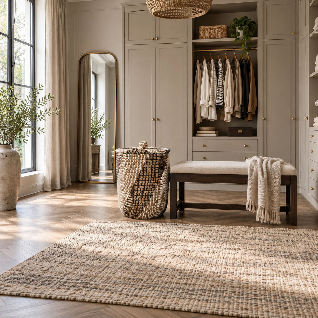 Runder Wäschesammler aus Seegras mit geschlossenem Deckel und ca. 65 Litern Volumen neben einer Sitzbank im Ankleidezimmer.