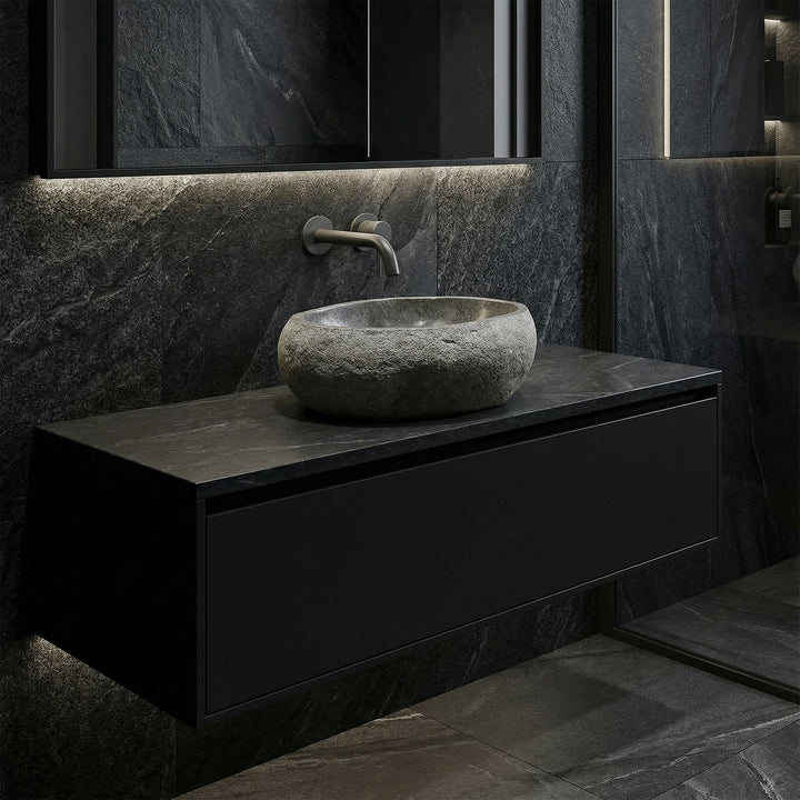 Lavabo en pierre sombre dans une salle de bain moderne sur meuble bas flottant, avec fixations murales et éclairage réduit